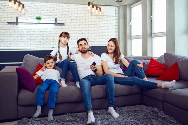 Une famille avec une télécommande regarde la télévision dans la chambre . — Photo