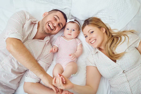 Une famille heureuse joue avec un tout-petit sur un lit à l'intérieur . — Photo