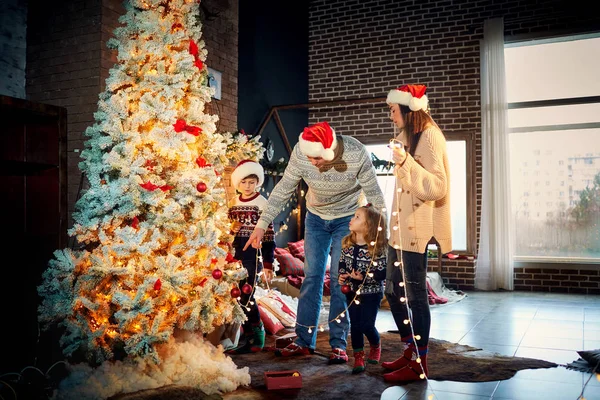 Μια ευτυχισμένη οικογένεια να στολίζει ένα χριστουγεννιάτικο δέντρο στο σπίτι. — Φωτογραφία Αρχείου