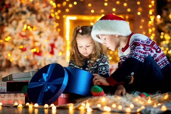 Kinder mit Weihnachtsmütze spielen an Heiligabend. — Stockfoto