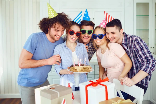 Vänner med tårta med ljus firar födelsedag på en fest. — Stockfoto