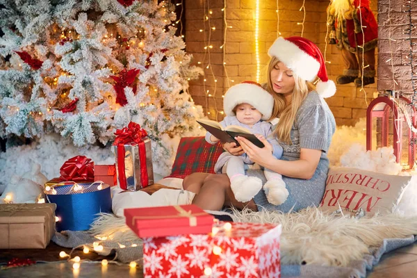 Mother with baby in a hat of Santa Claus in the Christmas room. — Stock Photo, Image