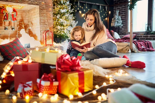 Anne ve çocuk Noel gününde bir kitap okurken. — Stok fotoğraf