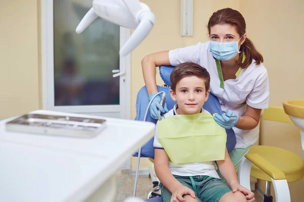 Un niño con un dentista en un consultorio dental . — Foto de Stock