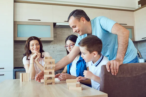 A cheerful family plays board games at home.