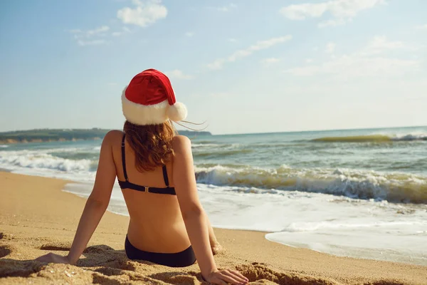 Dziewczyna w santa hat na plaży nad morzem na Boże Narodzenie. — Zdjęcie stockowe