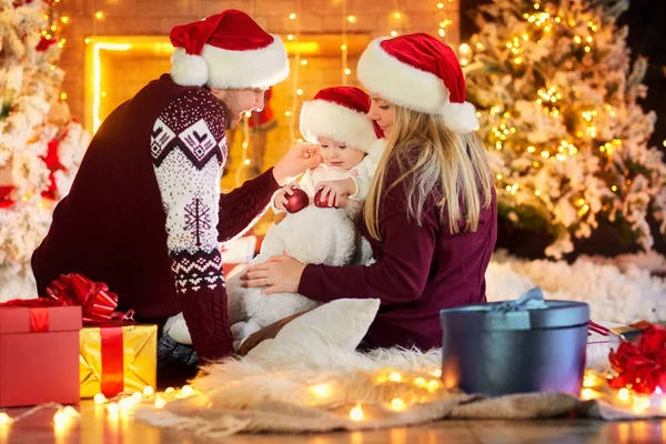 Met een baby op een kamer Kerstmis en gelukkige familie. — Stockfoto