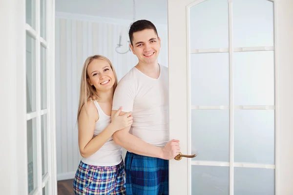 Um casal feliz em seu pijama convida para sua casa . — Fotografia de Stock