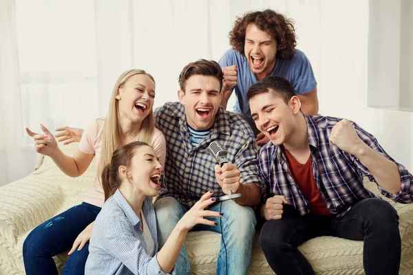 A group of friends with a microphone are singing fun songs indoo — Stock Photo, Image