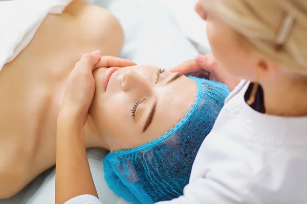 Estetista fa massaggio facciale ad una giovane donna . — Foto Stock