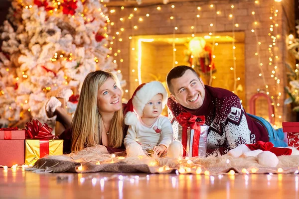 Happy family with a baby in a Christmas room. — Stock Photo, Image