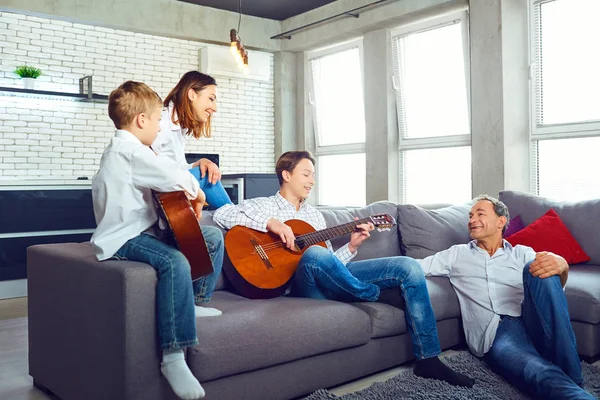Šťastná rodina s kytara zpěv písní v místnosti — Stock fotografie