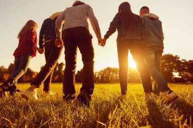 Arkadan görünüm. Bir grup arkadaşıyla birlikte elele par gün batımında