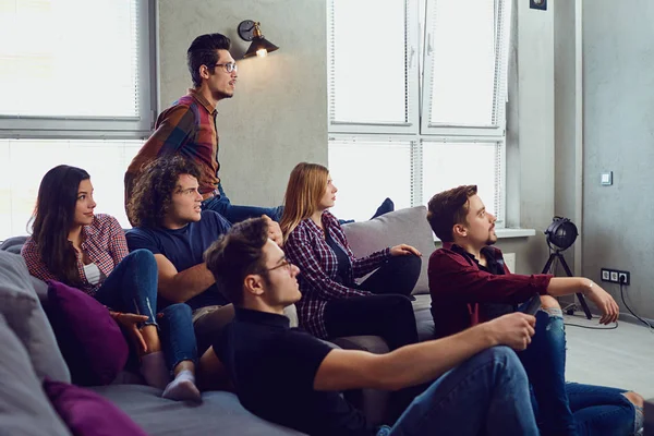 Un grupo de amigos se divierten viendo la televisión en la habitación . — Foto de Stock