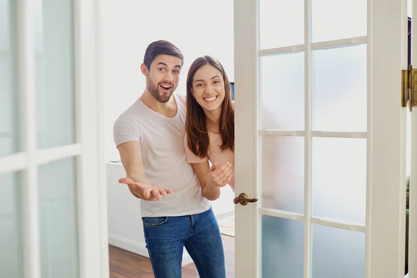 Um casal com sorrisos abre a porta para sua casa . — Fotografia de Stock