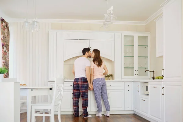 Visão traseira de um jovem casal de pijama na cozinha . — Fotografia de Stock
