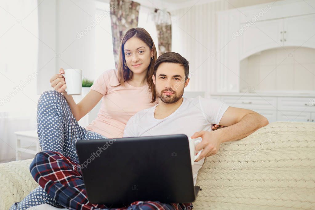 Husband and wife sitting with a laptop read at home.