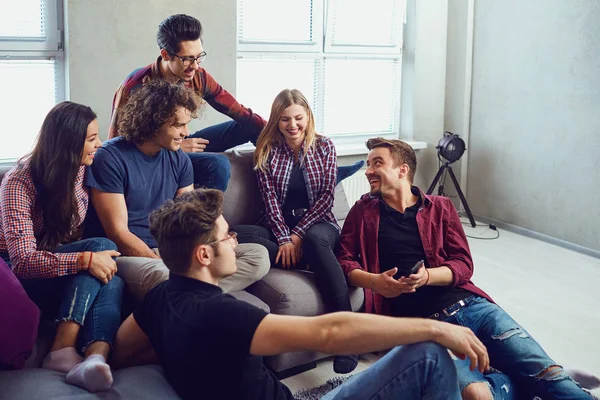 Een groep vrienden op een bijeenkomst praten samen zitten op een zo — Stockfoto