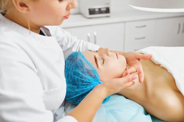 Schoonheidsspecialist maakt gezichtsmassage aan een jonge vrouw. — Stockfoto