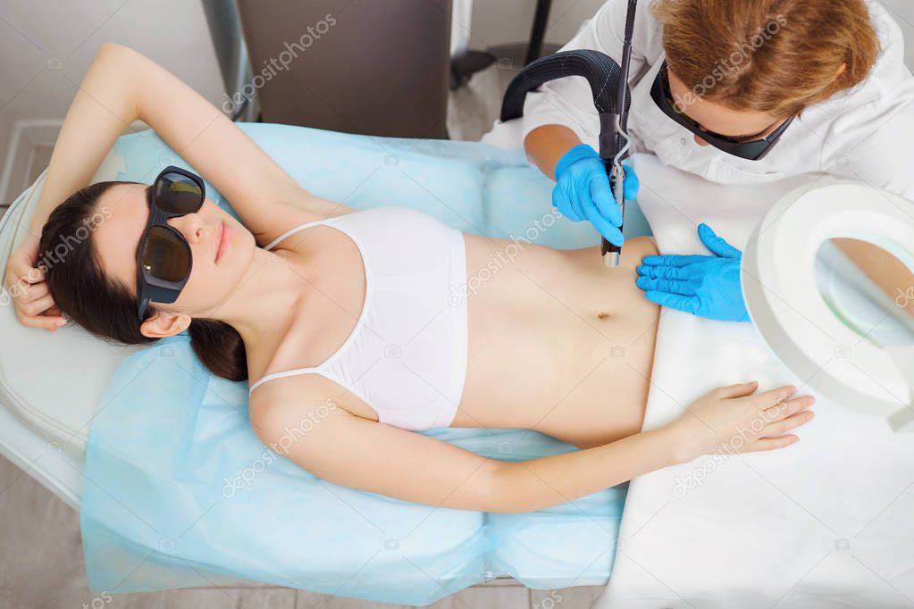 Laser hair removal on her stomach on the body of a young woman i