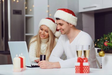 A couple shopping on the internet at home for Christmas clipart