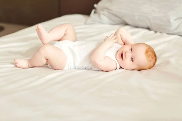 O bebê deitado na cama parece . — Fotografia de Stock