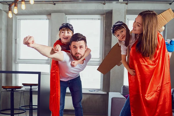 Een gelukkige familie speelt in superhelden binnenshuis — Stockfoto