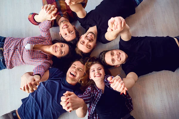 Bovenaanzicht. Een groep vrienden lachen op de vloer liggen. — Stockfoto