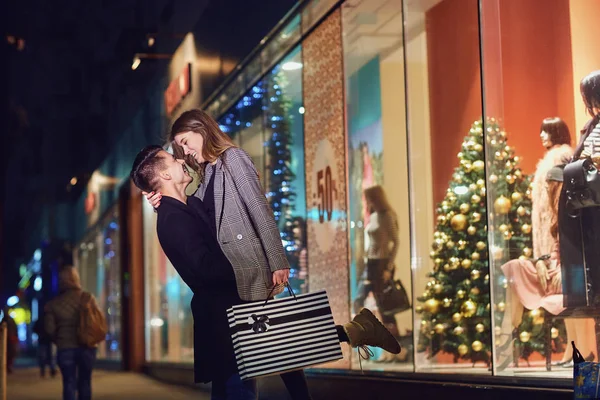 Una joven pareja con paquetes está de compras en la tienda frente a t — Foto de Stock
