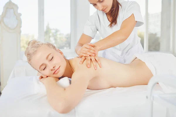 Massage corporel. Femme blonde dans le salon de spa faisant massage du corps . — Photo