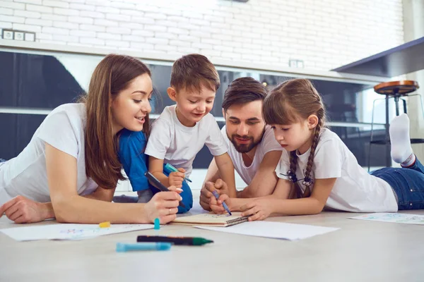 Uma família se baseia no papel deitado em seu tempo livre no chão . — Fotografia de Stock