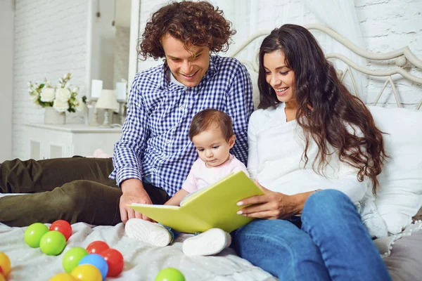 Keluarga bahagia membaca buku dengan seorang anak di dalam ruangan . — Stok Foto