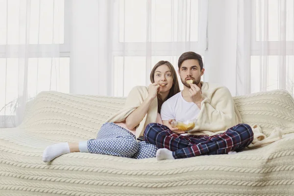 Um jovem casal sentado no sofá assistindo a uma interessante TV  . — Fotografia de Stock