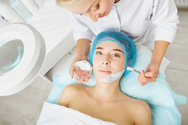Kosmetolog gör skönhet mask till en ung kvinna. — Stockfoto