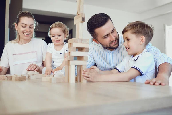 Une famille joue à des jeux de société assis à une table à l'intérieur . — Photo