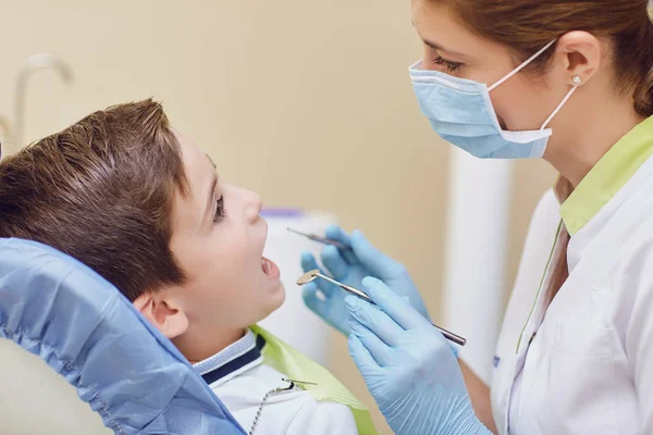 Tandarts behandelt een childs tanden met een jongen in een tandheelkundige kantoor — Stockfoto