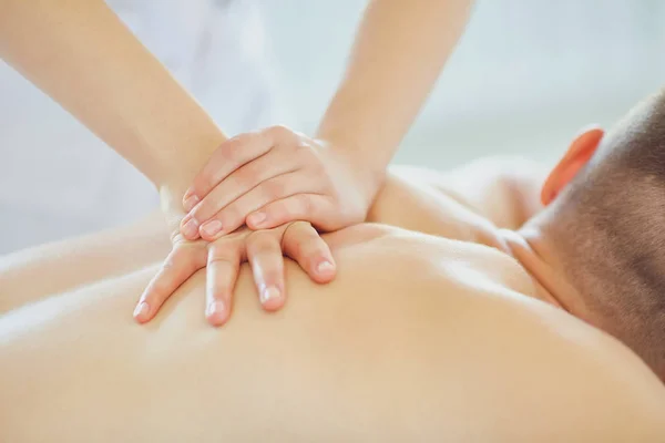 Una massaggiatrice fa massaggi a un uomo sdraiato su un tavolo . — Foto Stock