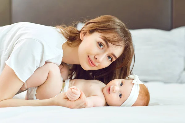 Madre jugando con el bebé en la cama . — Foto de Stock