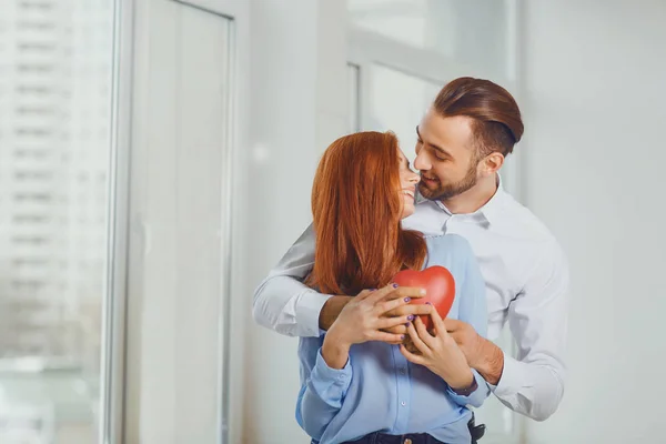 Pár se srdcem v jejich rukou proti oknu. — Stock fotografie