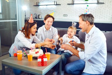 Bir aile bir mum pasta ile bir doğum günü partisi kutluyor.