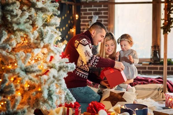 Met een baby op een kamer Kerstmis en gelukkige familie. — Stockfoto