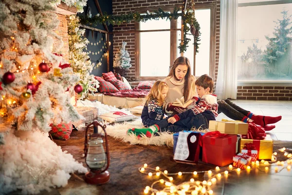 Mutter und Kinder lesen an Weihnachten ein Buch. — Stockfoto