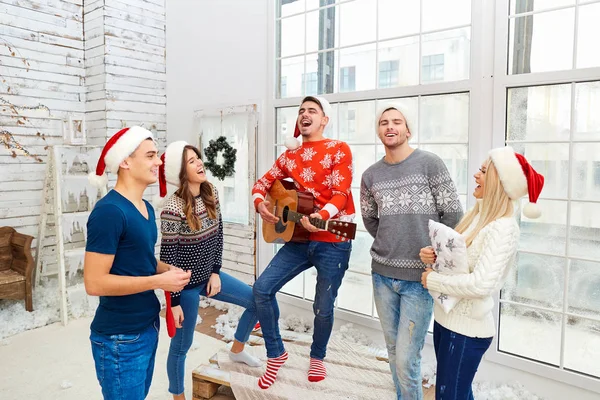 Μια ομάδα φίλων με κιθάρα και τραγουδώντας στο σπίτι για τα Χριστούγεννα — Φωτογραφία Αρχείου