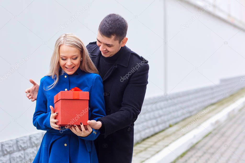 Romantic couple with gift in her hands outdoors.