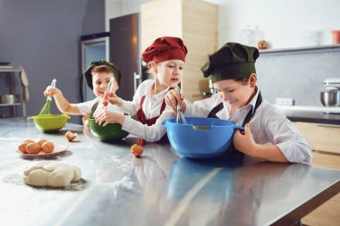 Bir grup çocuk mutfakta masada yemek pişirme