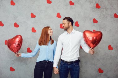 Gri bir arka plan üzerinde kırmızı kalp balon ile çift. 