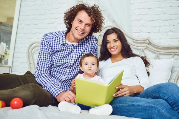 Mãe, pai e filho estão lendo um livro em casa — Fotografia de Stock