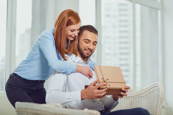 Paret ger en gåva med ögonen stängda i rummet . — Stockfoto