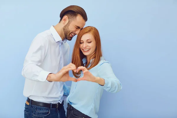 Casal apaixonado por um coração em um fundo azul . — Fotografia de Stock