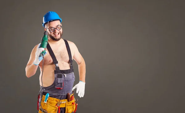 Der dicke komische Baumeister mit dem Bohrer. — Stockfoto